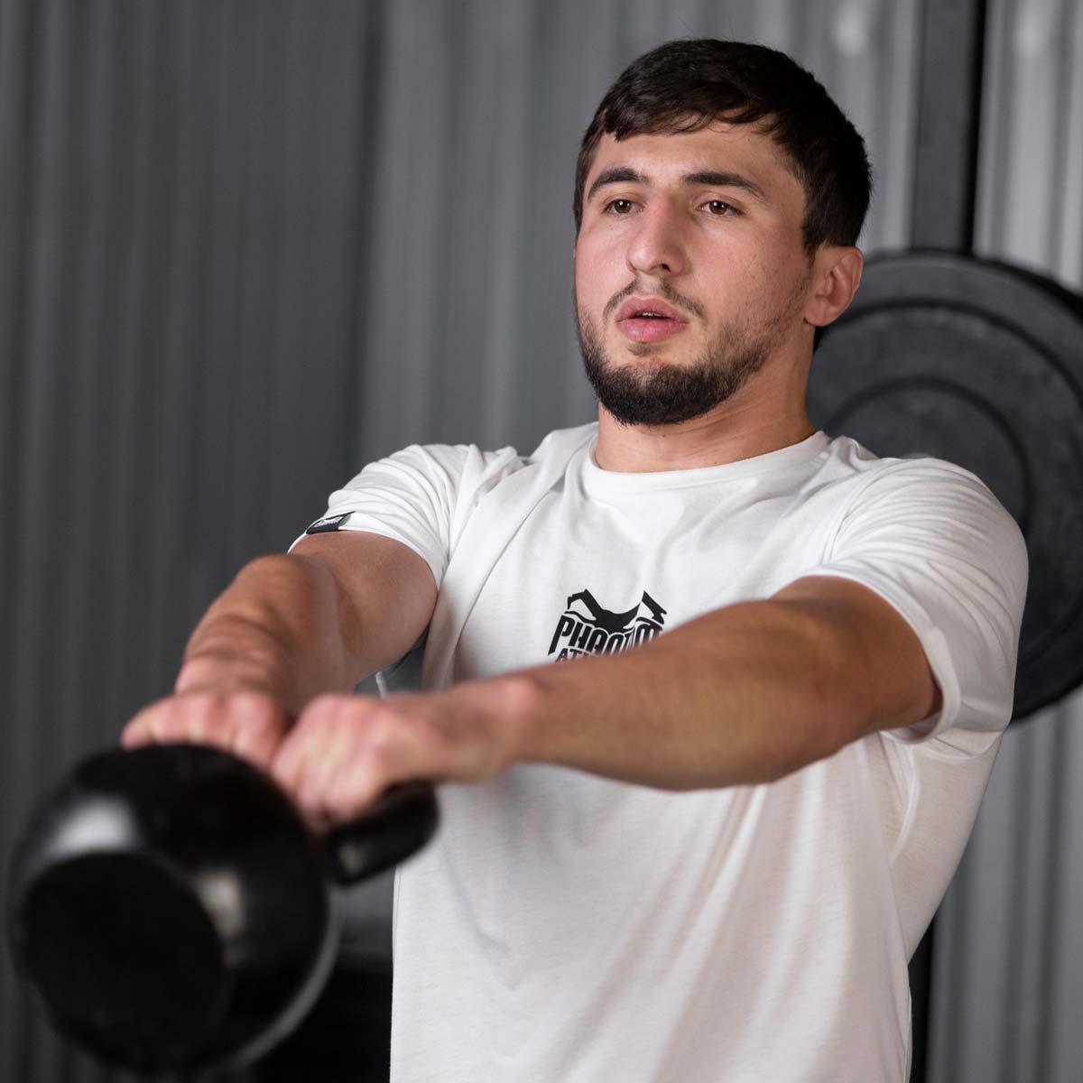 Phantom Athletics Kampfsport T-Shirt für Training und Straße, im bequemen Schnitt und aus hochwertiger Baumwolle. Hier in der Farbe Weiß. Getragen von Ringer Weltmeister Idris Ibaev.