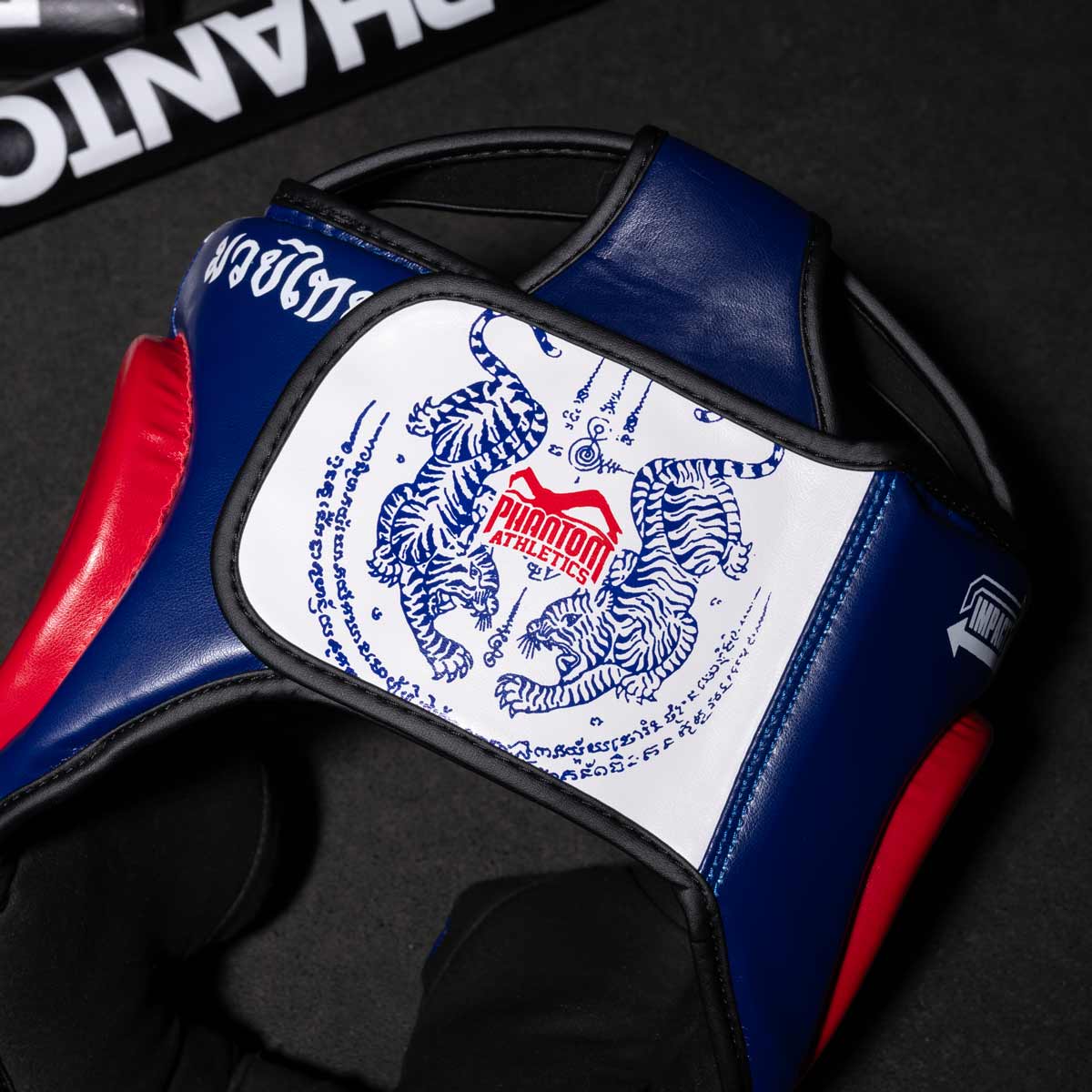 Phantom Muay Thai Kopfschutz für Thaiboxen und MMA Sparring, Wettkampf und Training. Im traditionellen Sak Yant Design und der Farbe Blau/Rot.