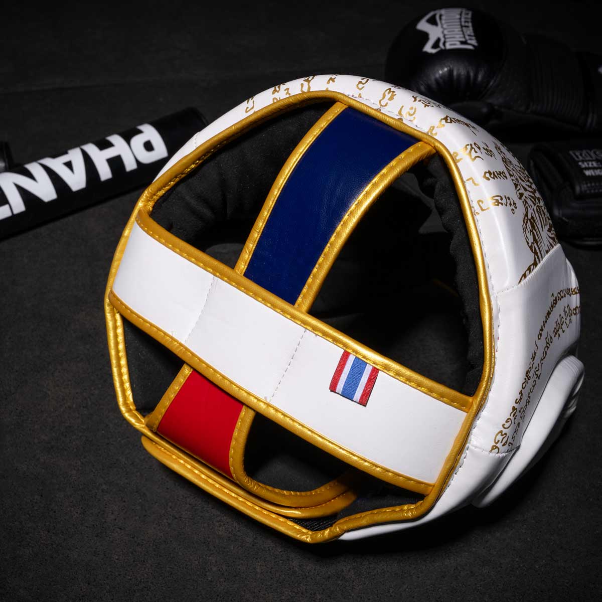 Phantom Muay Thai Kopfschutz für Thaiboxen und MMA Sparring, Wettkampf und Training. Im traditionellen Sak Yant Design und der Farbe Blau/Rot.